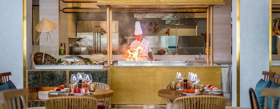 A man in a  white chef hat cooking something at Lua Grill & Bar 