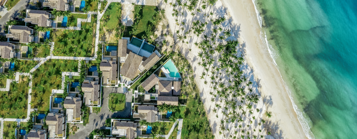 birds eye view of white sand beaches with white umbrellas lined in a row and the ocean at the New World Phu Quoc Resort in Vietnam