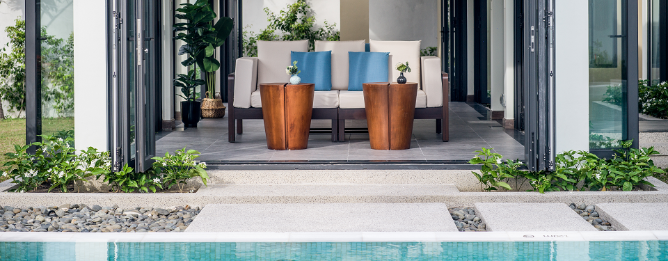 Phòng khách có hướng nhìn ra bể bơi với bàn gỗ và ghế sofa tại căn biệt thự Beachfront Pool Villa.