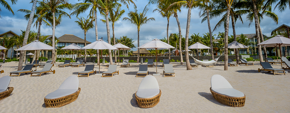 The blue sky, white sand with white umbrellas at the New World Phu Quoc Resort. 