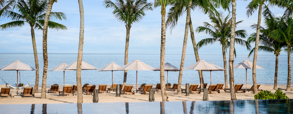 The blue sky, white sand with white umbrellas at the New World Phu Quoc Resort. 